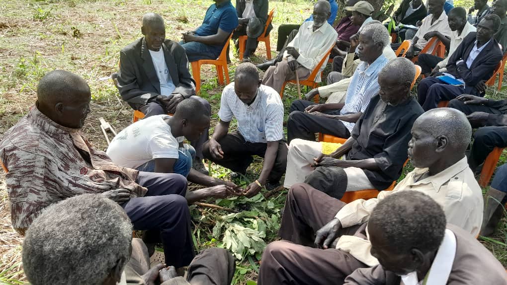 Elders gather to partake of an offering during a cleansing ritual exercise at Labworoyeng parish Acholibur sub county.